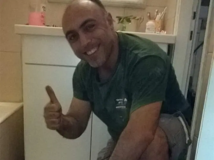 דודי מחייך ומרים אגודל בזמן עבודה בחדר רחצה